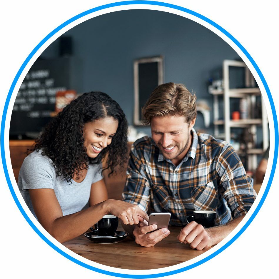 Circular image of a couple sat in a cafe, scrolling through an app on a shared mobile phone