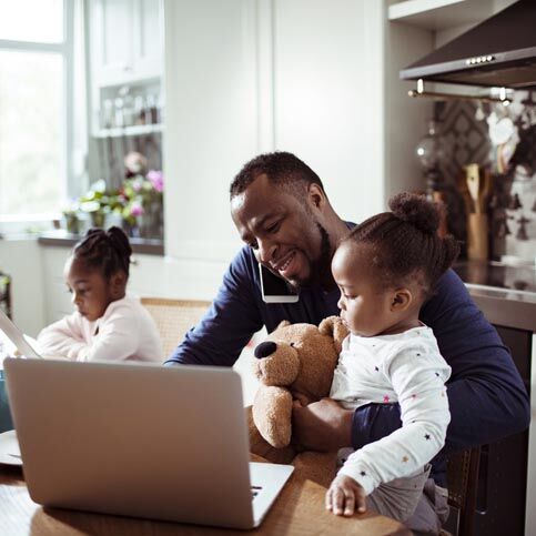 Close up of a young family using a laptop in the morning , while the father is talking on the phone