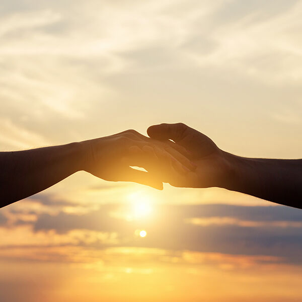 close up of hand-holding in front of a sunset