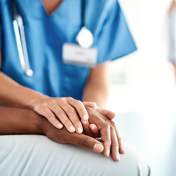 close up of a nurse holding a patient's hand