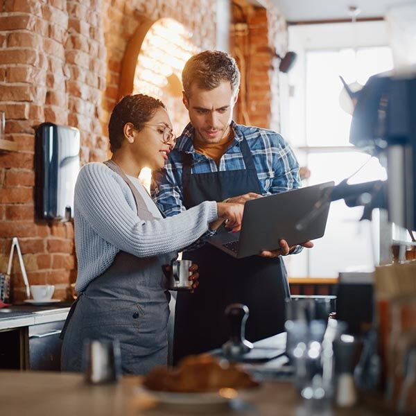 Barista and Cafe Owner Discuss Work Schedule and Menu on Laptop Computer
