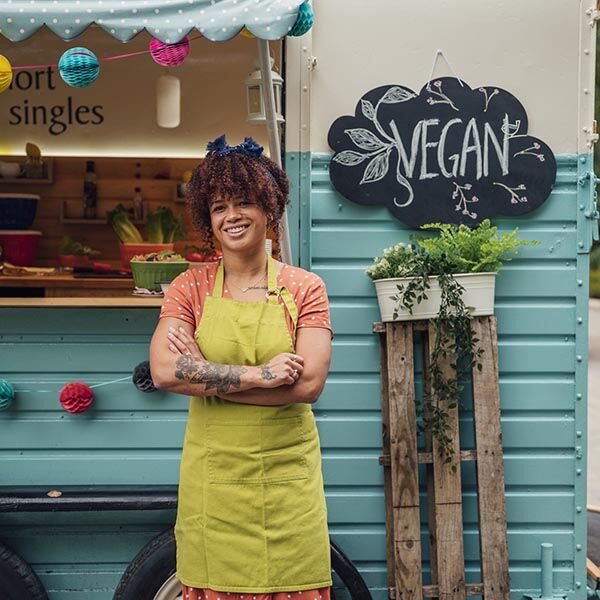 a food truck where a mixed race female hipster stands with her arms folded