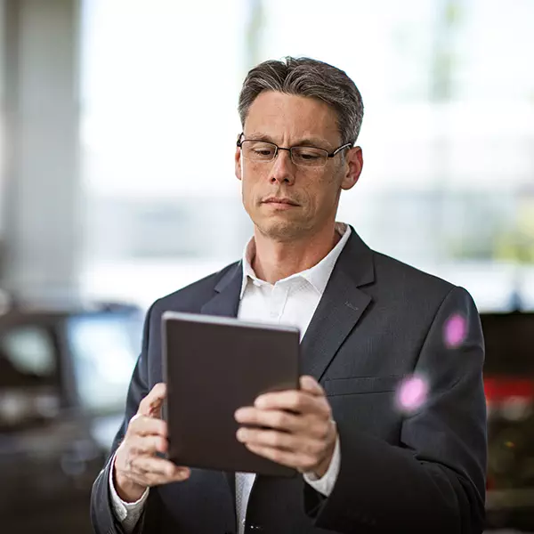 Senior car salesman reviews his marketing campaign insights on tablet device